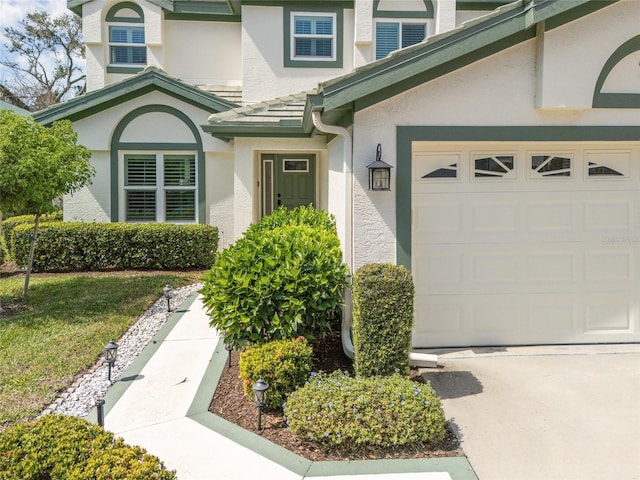 view of exterior entry with an attached garage and stucco siding