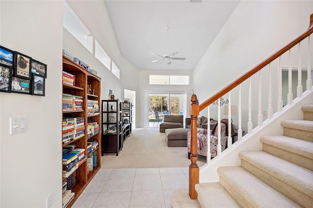 interior space with tile patterned floors, carpet floors, a towering ceiling, and a ceiling fan