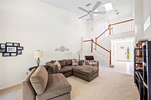 carpeted living room with tile patterned flooring, ceiling fan, baseboards, stairs, and a high ceiling