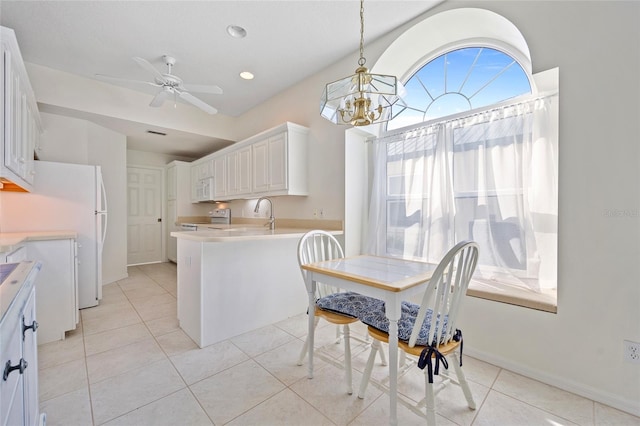 kitchen with light tile patterned floors, white appliances, a peninsula, and light countertops