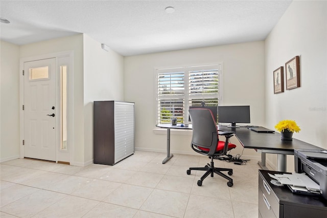 office space with light tile patterned floors, baseboards, and a textured ceiling