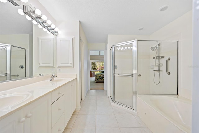 bathroom featuring tile patterned flooring, a shower stall, a textured ceiling, and a sink