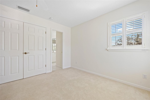 unfurnished bedroom with visible vents, a closet, carpet floors, baseboards, and ceiling fan