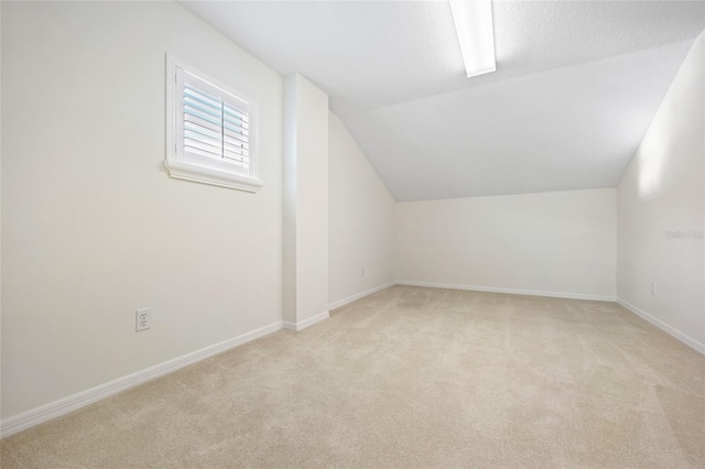 bonus room featuring baseboards, lofted ceiling, and light carpet