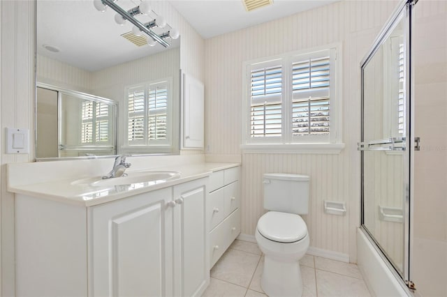 bathroom featuring vanity, baseboards, enclosed tub / shower combo, tile patterned flooring, and toilet