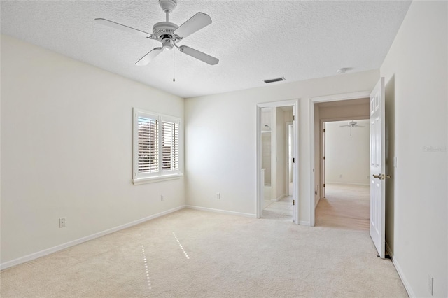 unfurnished bedroom with visible vents, ensuite bathroom, a textured ceiling, baseboards, and light colored carpet