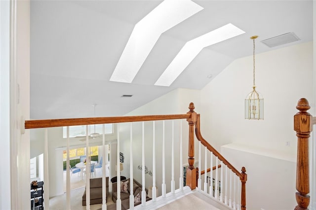 staircase featuring vaulted ceiling with skylight and visible vents