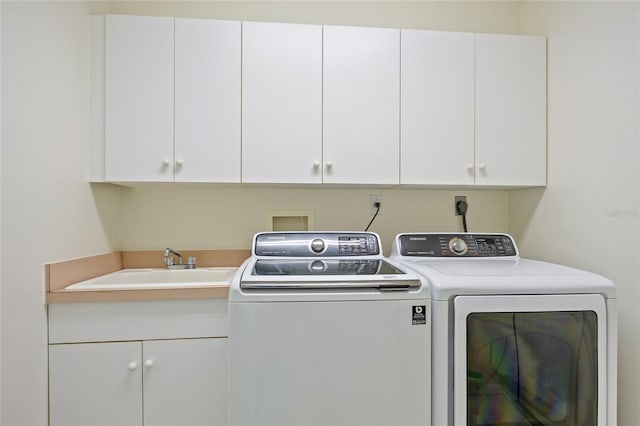 clothes washing area with cabinet space, washer and dryer, and a sink