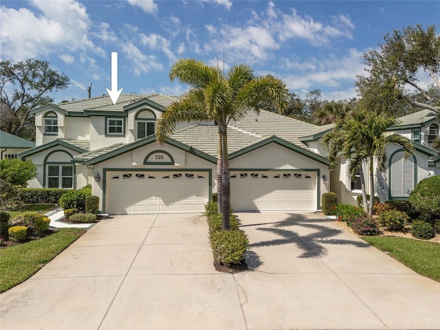 view of front facade with stucco siding, driveway, an attached garage, and a tiled roof