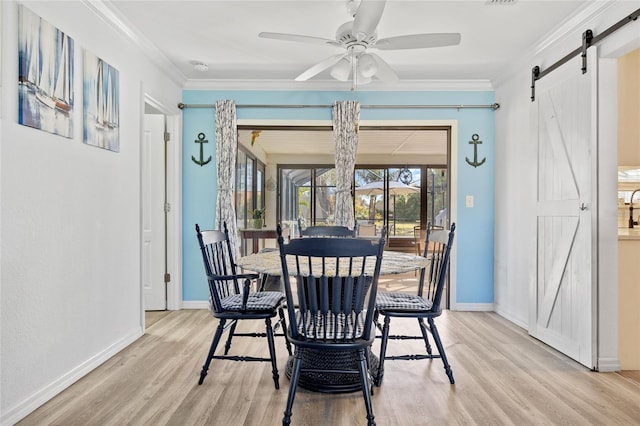 dining area featuring light wood-type flooring, a barn door, and crown molding