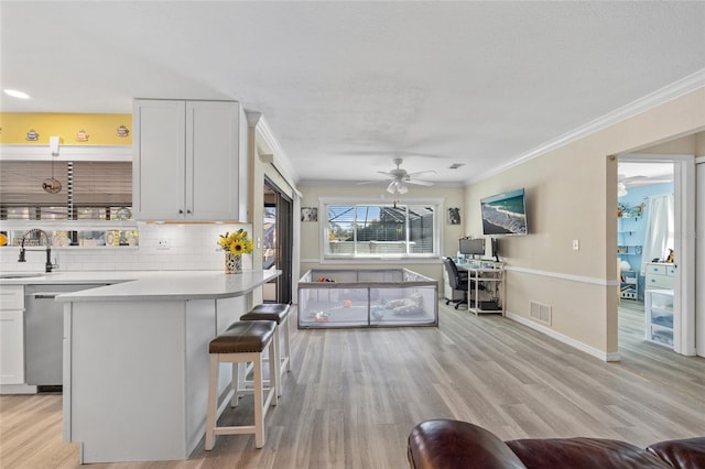 kitchen featuring visible vents, a kitchen bar, light wood-style floors, and ornamental molding