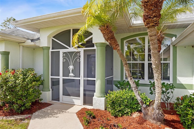 doorway to property with stucco siding and a shingled roof