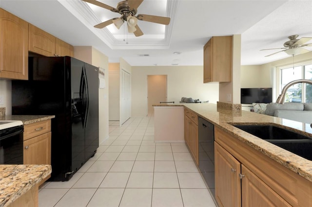 kitchen with a tray ceiling, light tile patterned floors, a sink, light stone countertops, and black appliances