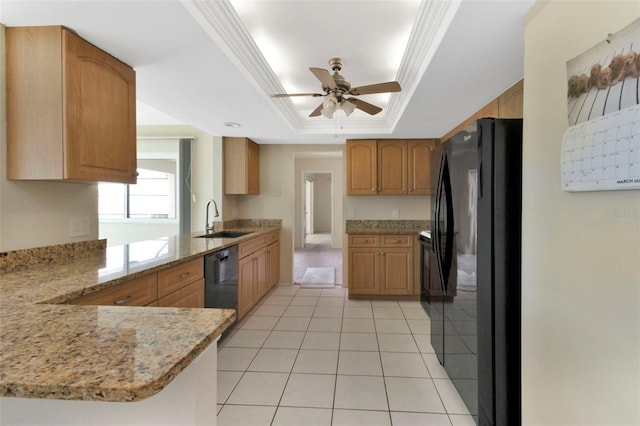 kitchen featuring a raised ceiling, ornamental molding, a peninsula, black appliances, and a sink