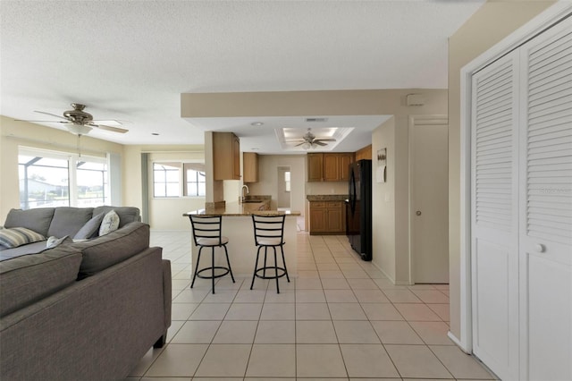 kitchen with ceiling fan, a peninsula, a sink, open floor plan, and freestanding refrigerator