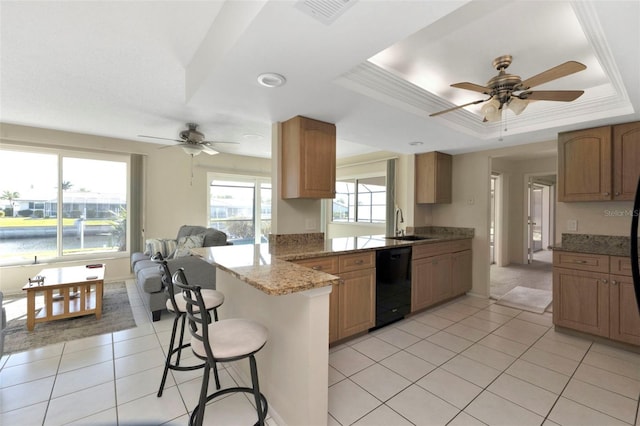 kitchen with black dishwasher, visible vents, a raised ceiling, a breakfast bar, and a peninsula