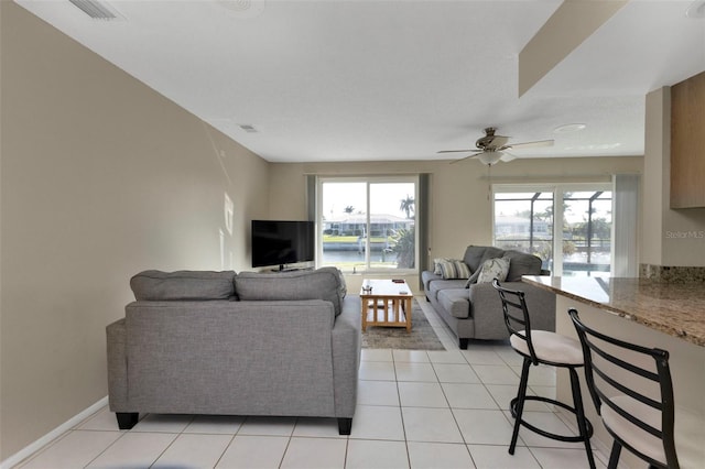 living area with light tile patterned floors, baseboards, visible vents, and a ceiling fan