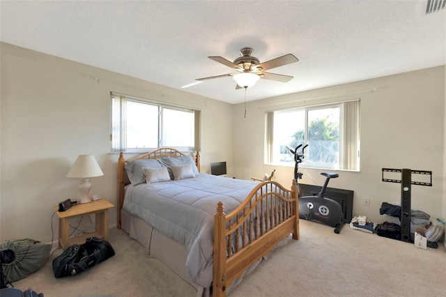 bedroom with a textured ceiling, carpet floors, multiple windows, and visible vents