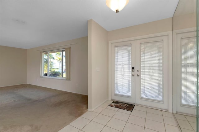 foyer featuring light carpet, light tile patterned flooring, and french doors