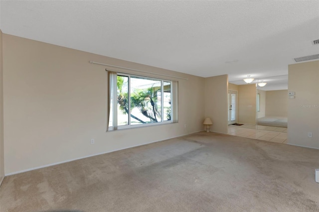 empty room with a textured ceiling, visible vents, and carpet flooring