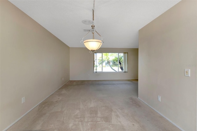 empty room featuring baseboards, lofted ceiling, visible vents, and light colored carpet