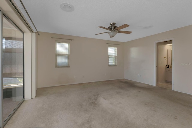 spare room with light carpet, ceiling fan, and a wealth of natural light