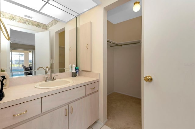 bathroom featuring visible vents, a walk in closet, and vanity