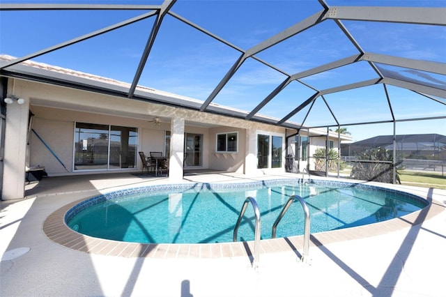 outdoor pool with a patio, glass enclosure, and a ceiling fan