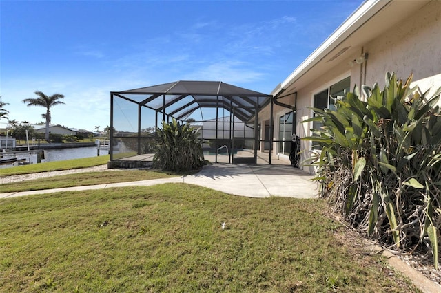 view of yard featuring a lanai, a patio area, and a water view