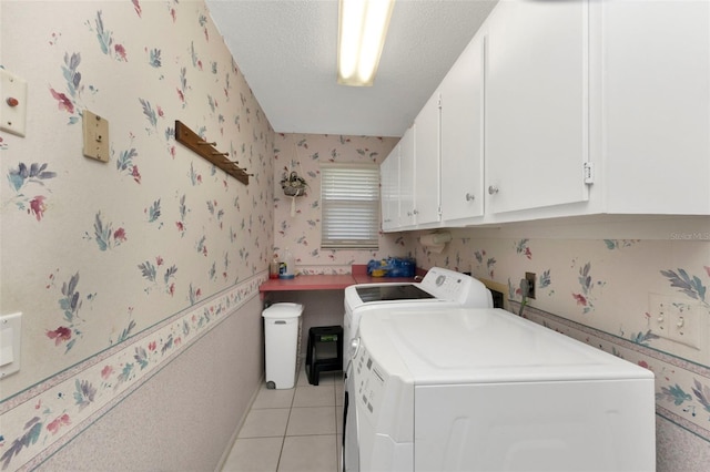 clothes washing area featuring light tile patterned floors, a textured ceiling, separate washer and dryer, cabinet space, and wallpapered walls