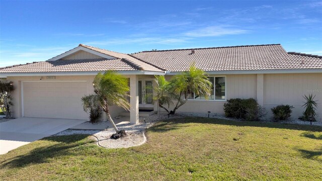 ranch-style house featuring a garage, driveway, a front yard, and a tiled roof
