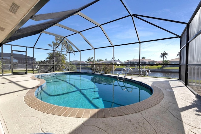 outdoor pool with glass enclosure, a patio area, and a water view
