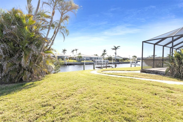view of yard featuring a water view, glass enclosure, and a dock