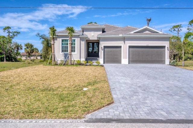 view of front of home with an attached garage, decorative driveway, a front yard, and stucco siding