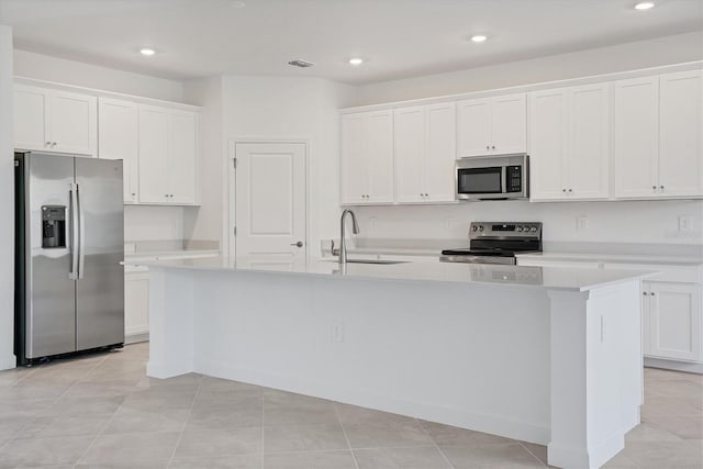 kitchen with appliances with stainless steel finishes, light countertops, a kitchen island with sink, and a sink