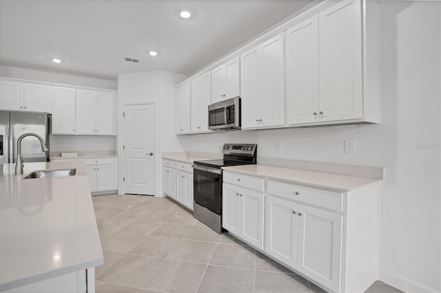 kitchen with appliances with stainless steel finishes, light countertops, visible vents, and a sink