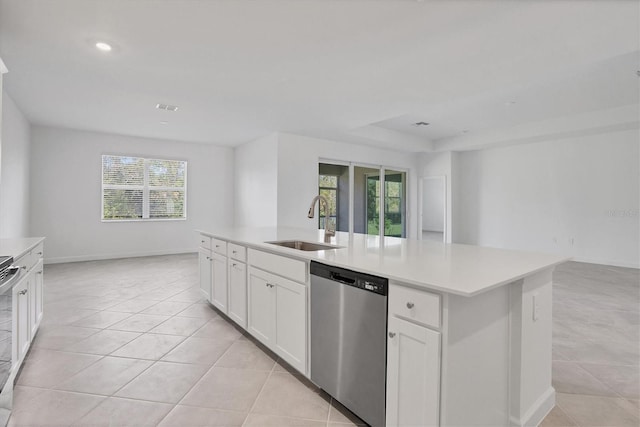 kitchen featuring a kitchen island with sink, a sink, open floor plan, light countertops, and stainless steel dishwasher