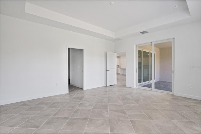 spare room featuring visible vents, a tray ceiling, and baseboards