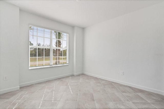 tiled spare room featuring baseboards