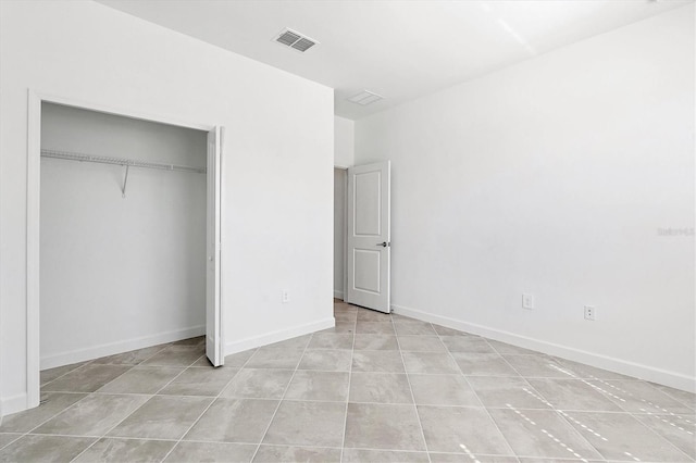 unfurnished bedroom featuring a closet, visible vents, baseboards, and light tile patterned floors