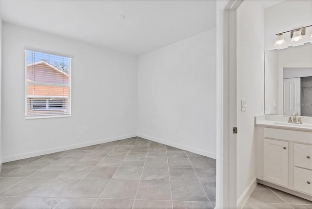 interior space featuring light tile patterned floors, a sink, and baseboards