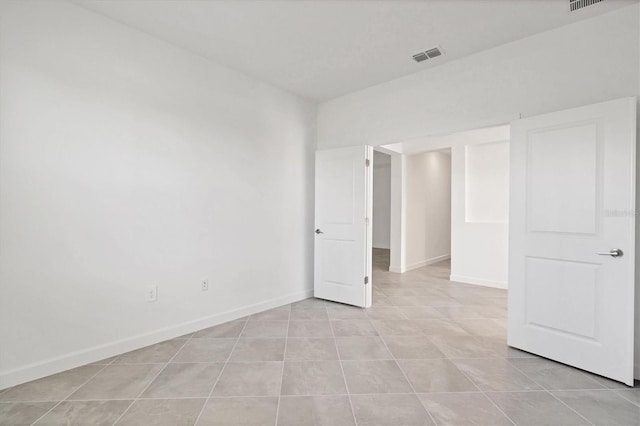 unfurnished room featuring light tile patterned flooring, visible vents, and baseboards