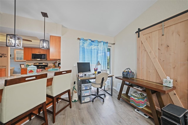 office with light wood-style floors, ceiling fan, and a barn door