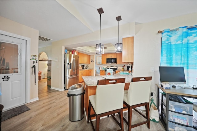 kitchen featuring a raised ceiling, visible vents, appliances with stainless steel finishes, light wood-style floors, and a peninsula