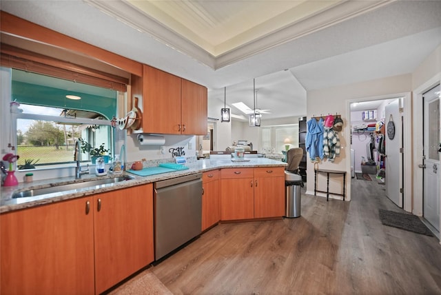 kitchen with light wood-style flooring, a peninsula, a healthy amount of sunlight, stainless steel dishwasher, and a sink