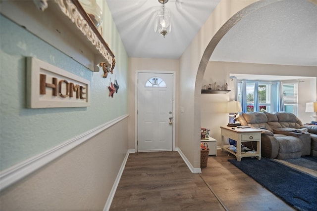 foyer with arched walkways, baseboards, and wood finished floors