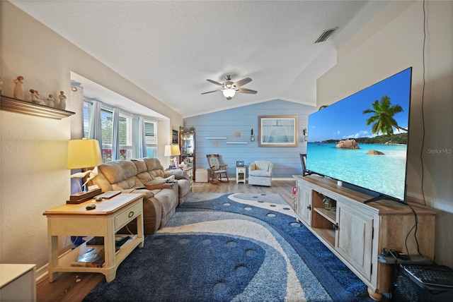 living area featuring visible vents, ceiling fan, vaulted ceiling, a textured ceiling, and wood finished floors