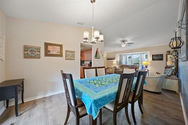 dining area with visible vents, baseboards, wood finished floors, and ceiling fan with notable chandelier