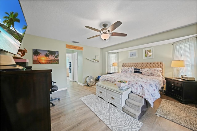 bedroom featuring a textured ceiling, multiple windows, wood finished floors, and visible vents