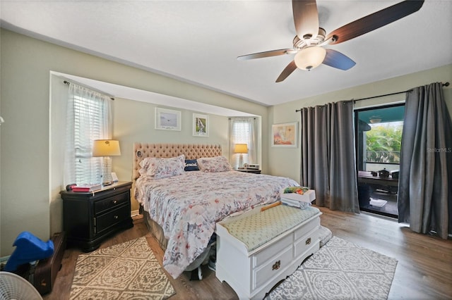 bedroom with a ceiling fan, access to outside, multiple windows, and wood finished floors